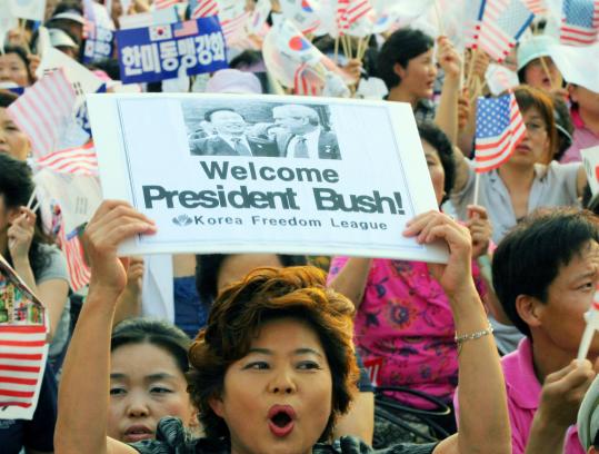 A woman displayed pictures of President Bush and his South Korean counterpart, Lee Myung-bak, yesterday in Seoul.