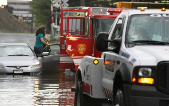 A firefighter carried a pregnant women named Aracelis Fontenot to safety yesterday after her car became flooded during heavy rains on Third Street in Everett.