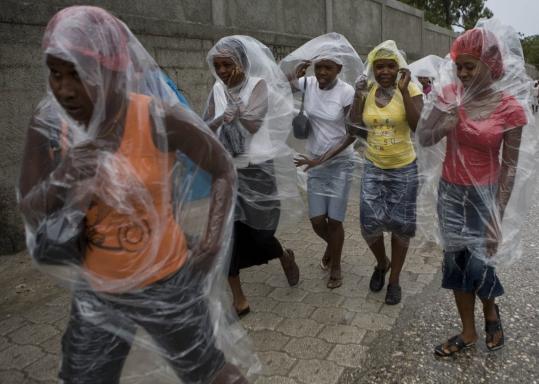 People covered themselves from the rain yesterday as Hurricane Gustav headed into Port-au-Prince, Haiti. One man was killed in a landslide in the mountain town of Benet.