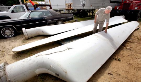 Aeronautica Windpower cofounder Brian Kuhn examines old turbine blades at the company's Plymouth yard.
