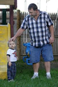 Neighbor David Powers, with his son in his backyard, calls the pig farm stench unbearable.