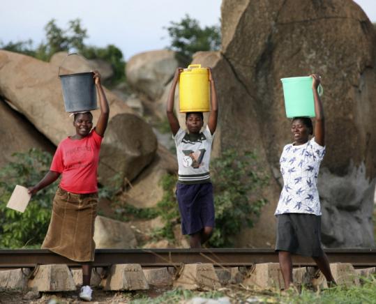 Women carried buckets of water in Budiriro near Harare, Zimbabwe yesterday, where a cholera epidemic is killing hundreds, as the nation's clinics run out of drugs.