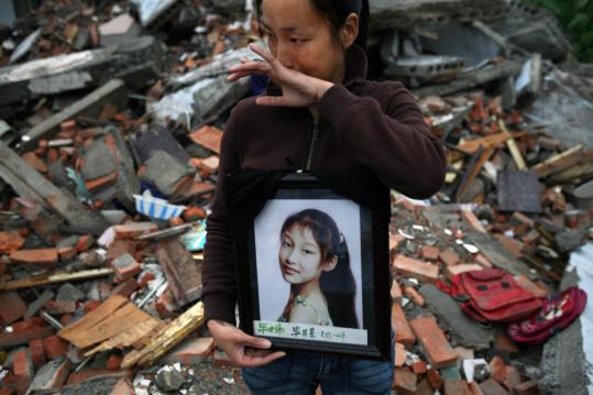 A mother wept on May 28 while holding a picture of her daughter, one of the children killed in the collapse of No. 2 Primary School in the town of Fuxin, where at least 127 students died.