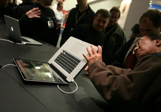 Macworld attendees check out display models of the new MacBook Pro laptops yesterday.