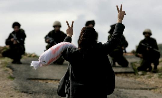 A Palestinian woman protesting the Israeli military operation in Gaza signalled her defiance yesterday as she faced Israeli soldiers in the West Bank village of Bilin, near Ramallah.