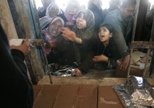 Palestinians sought food aid at a United Nations food distribution center in Shati refugee camp in Gaza City yesterday. Israeli forces pounded dozens of targets and edged closer to Gaza City, while southern Israel came under renewed rocket fire.