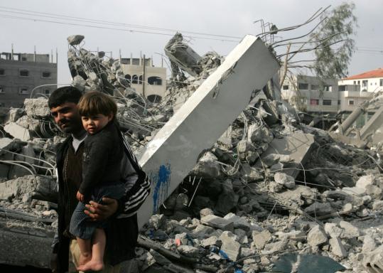 A Palestinian man carried a child as he passed the rubble of the Taha mosque after it was struck yesterday by Israeli warplanes in the town of Beit Lahia in the northern Gaza Strip.