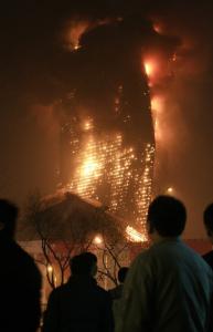 A crowd watched an unoccupied skyscraper as it became consumed by flames last night during a fireworks display. The building was to have housed a luxury hotel.