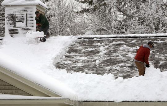 Randy Leclair (left) and Ryan Gurney shoveled heavy snow off the roof of a business in Brunswick, Maine.