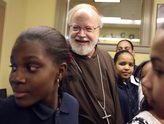 Adelciene Moreno (left) and Andrea Lopes flanked Cardinal Sean P. O'Malley at the Teen Center at St. Peter's Parish in Dorchester. As the archdiocese consolidates parishes and schools, O'Malley said the center showed a commitment to the city.