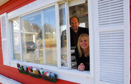 Kristen and Greg Caira look out from inside their drive-up coffee shop in the parking lot of Benny's Plaza on Court Street in Plymouth.