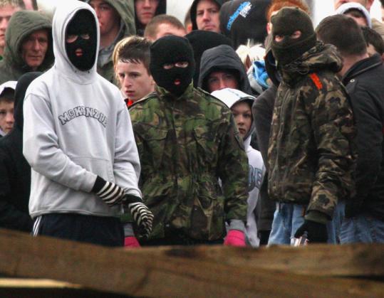 Masked Irish nationalists protested in the hometown of Colin Duffy, a suspect in the deaths of two British soldiers.