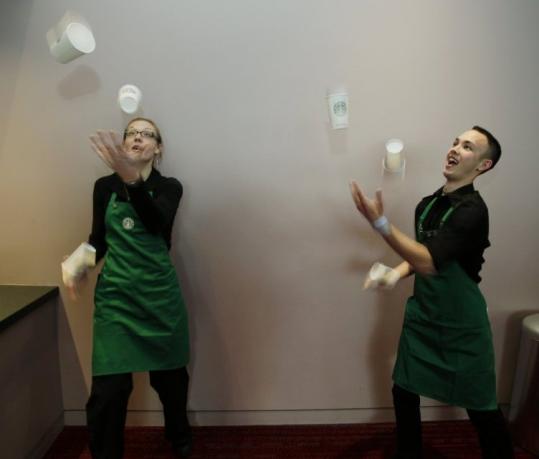 Baristas Carrie Veatch and Andrew Flewelling juggle coffee cups yesterday prior to Starbucks Corp.s annual meeting. (Ted S. Warren/ Associated Press) 