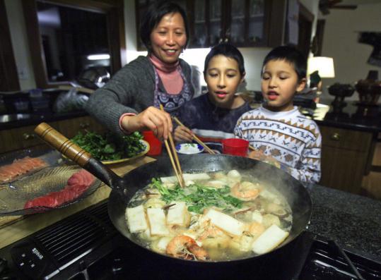 Zhuqing Li and her sons, Daniel and William, prepare matzo ball hot pot in a wok.