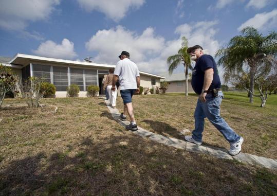 Guy Hart (right) and his friend Ralph Sawyer, both of Maine, look over the backyard of a bank-owned property in Cape Coral, Fla., recently.