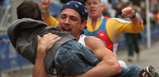 David Paterson of Tewksbury carries a friend's son across the Boston Marathon finish line.