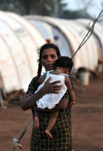 A displaced Tamil woman walked with her child among the tents in a guarded camp.