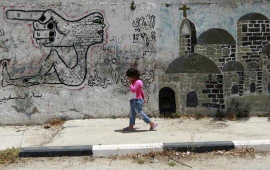 A Palestinian girl walked past graffiti on a wall in Aboud, West Bank. Israel has been heavily criticized over settlements there.