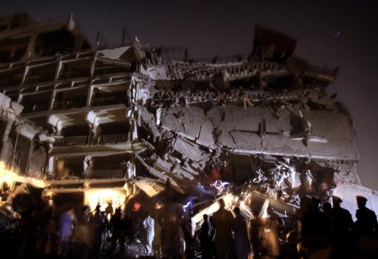 Pakistanis gathered next to a partially collapsed hotel after an explosion in Peshawar yesterday. Suicide attackers in a truck launched an assault on a luxury hotel commonly used by foreigners, firing guns and setting off a blast that killed 11 people.