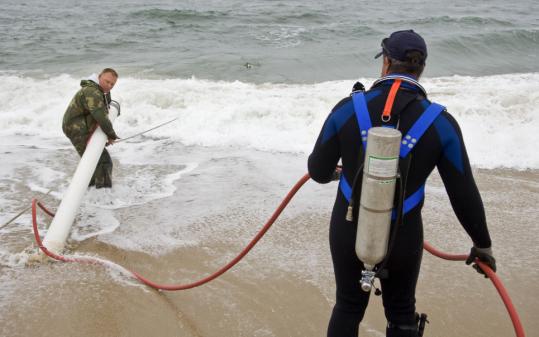 At South Beach on the Vineyard, tender Larry Weinmann (left) and diver Robert Rozzi demonstrated a vacuum that removes sand, used in the recovery of bombs.