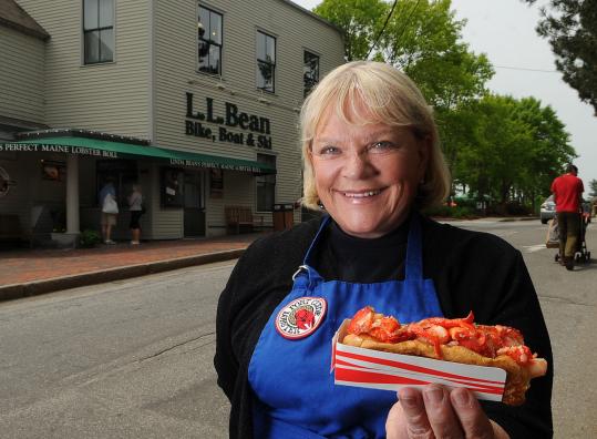 Linda Bean, of the famous L.L. Bean family, is the champion for Maine lobsters. She has lobster roll kiosks in Freeport and Hull, Mass., and plans to open more in the near future. Below: Sylvain Dugre and Susan Bujold of Quebec City enjoy Bean’s efforts.