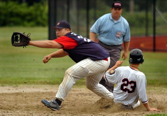 Hanover’s John Spitz slides safely into first on his infield hit as Whitman-Hanson’s Anthony Glynn waits for the throw.
