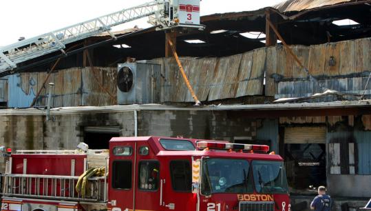 Boston firefighters worked at the scene of a four-alarm fire that destroyed a fish wholesaler and damaged three other businesses.