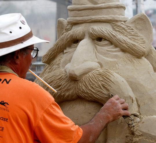 Justin Gordon of Groveland worked on “It’s No Yolk’’ yesterday during the annual New England Sand Sculpting Festival at Revere Beach. He held a straw in his mouth to blow away sand as he cut to create the sculpture.