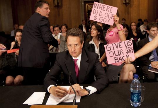 Treasury Secretary Timothy Geithner waited for the start of a Congressional Oversight Panel hearing yesterday in Washington, as protesters held up signs referring to government bailout funds for the banking industry.