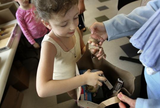 Seven-year-old Sadie Goldman of Boston helps fill bags with other Family Table volunteers.