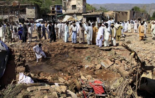 Pakistani villagers stood beside a crater after a suicide car bombing yesterday in Kohat, 40 miles from Peshawar. The bomb destroyed a two-story hotel and several shops in northwestern Pakistan.