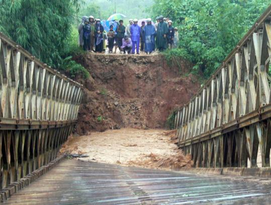 Residents huddled at a collapsed bridge yesterday in Kon Tum, in Vietnam’s Central Highlands. Authorities evacuated more than 170,000 people as Typhoon Ketsana approached.
