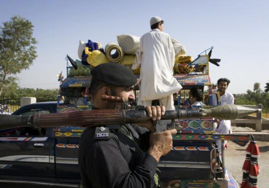 A police officer stood guard as displaced people fled Waziristan, where Pakistani forces are fighting militants.