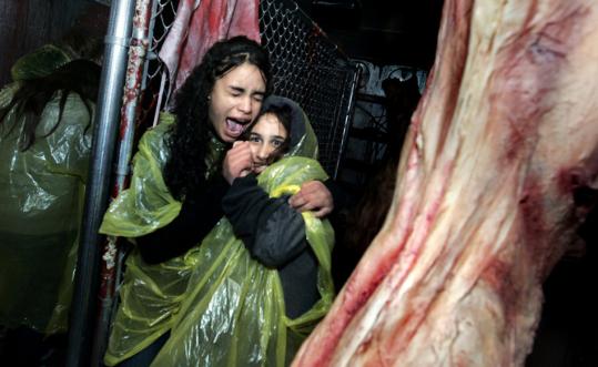 Alyssa Marks (left) and Atlanta Juares clung to each other as they bumped into a rubber torso hanging from a meat hook at SpookyWorld in Litchfield, N.H.