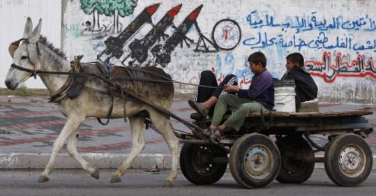 Palestinian boys drove their cart past a wall covered with graffiti showing rockets in Gaza City yesterday.