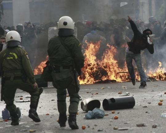 A protester threw a stone at riot police during a demonstration held in Athens yesterday to mark the one-year anniversary of a police shooting in which a teen was killed.