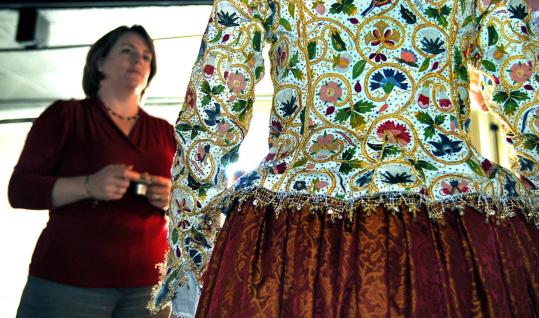 Tricia Wilson Nguyen looks at the embroidered reproduction 17th-century jacket modeled by Elizabeth Rolando. With the aid of more than 250 needlework volunteers, the jacket took three years to finish.