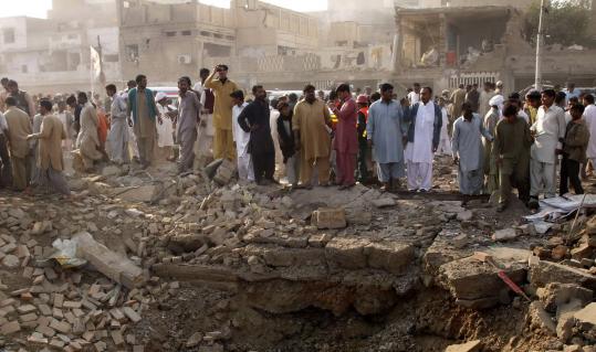 People gathered yesterday near a crater in Dera Ghazi Khan, Pakistan. The bomb exploded near a market and a politician’s home.