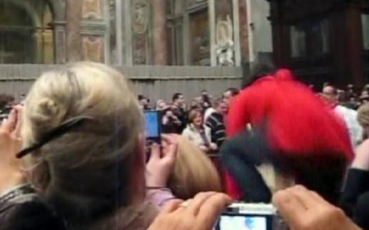 This amateur video shows the blurry image of a woman (right) jumping a barricade just before attacking Pope Benedict XVI.