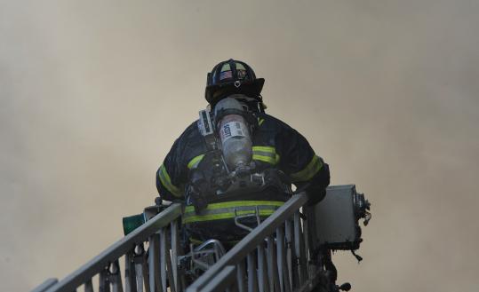 Above, a firefighter climbed a ladder amid smoke from the six-alarm blaze that struck a Malden apartment building.