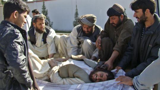 Afghans rushed a wounded man to a hospital yesterday in Lashkar Gah, Helmand Province. The man was injured when protesters clashed with Afghan and foreign security forces.