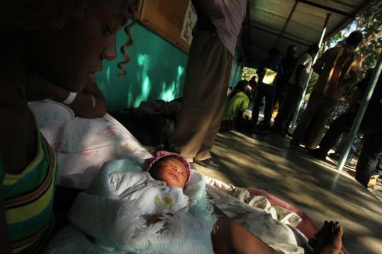 Erline Michelle held her one-week-old niece as they waited to be seen at a hospital a Massachusetts disaster medical team set up yesterday in a schoolyard in Port-au-Prince.