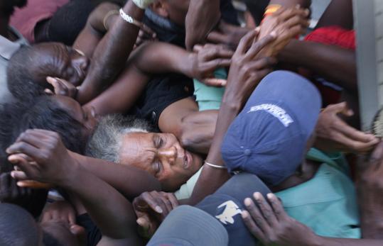 An elderly Haitian woman was caught in the crush of people struggling for food and water distributed by a relief agency yesterday in Petion Ville, Haiti. At least two small aftershocks rattled the country, compounding the distress of millions.