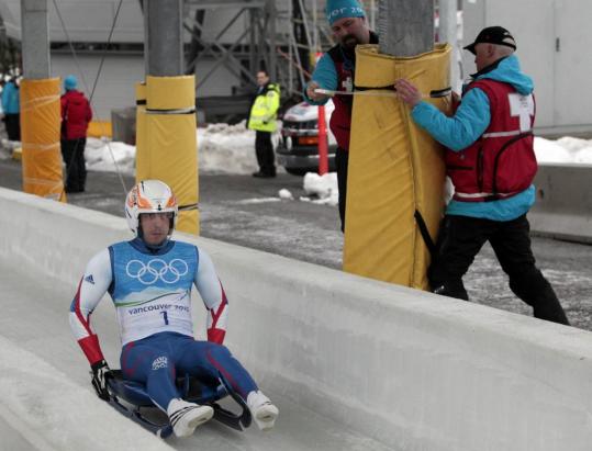 While French luger Thomas Girod trains, workmen add protective measures near the finish line of the Whistler Sliding Centre.