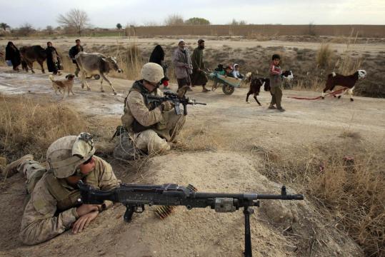 Afghans walked in front of US Marines in Marja yesterday, where Taliban fighters remained in the western part of town.