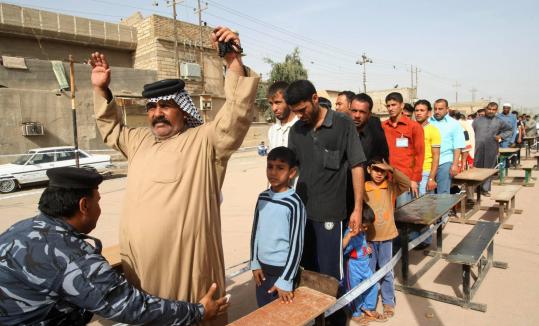 A policeman frisked a man in line to vote at a polling center in Basra, Iraq. At least 38 were killed in Baghdad.