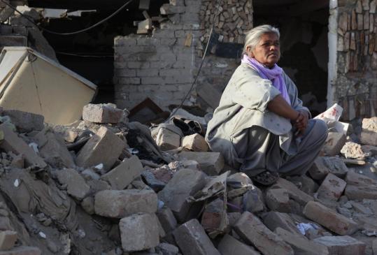 A woman sat in the rubble of her house yesterday after a suicide  car bomb exploded outside a Punjab Province police building in Lahore.