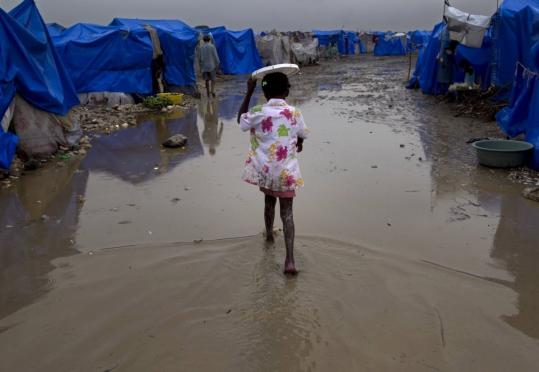 A girl walked in a  camp for homeless earthquake survivors during heavy rain in  Port-au-Prince, Haiti. People used sticks and their hands to dig  drainage ditches around their tarps.