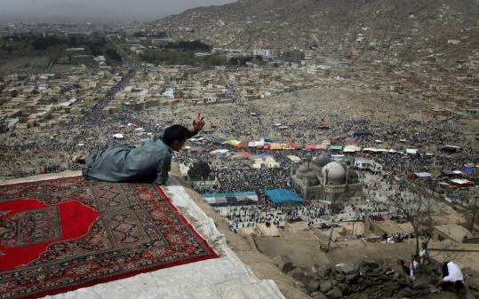 A   youth watched the celebration of Nowruz, the Afghan new year, from a   roof on the hilltop at the Kart-e-Sakhi shrine in Kabul.