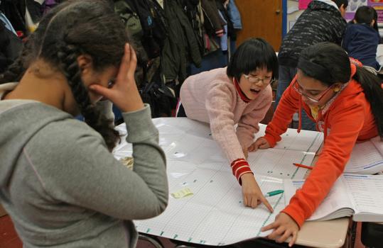 Fifth-grader Michelle Serverino thinks while going over a math chart with classmates Stephanie Mei and Jeilene Amparo at the Manassah E. Bradley School in East Boston.